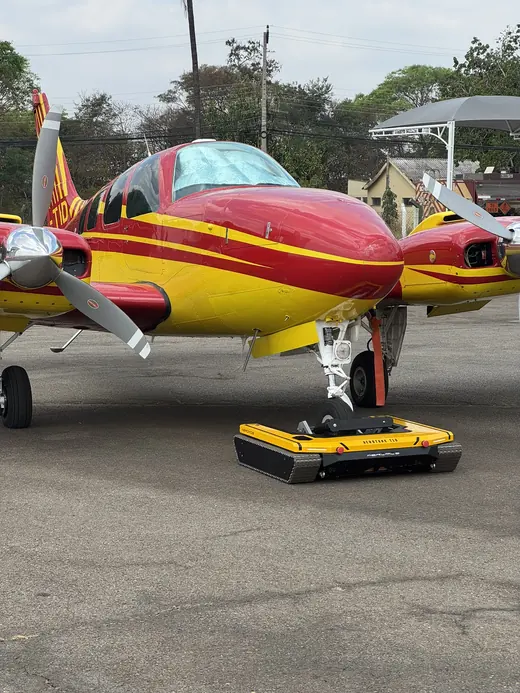 AEROTANK engaged on the nose wheel of a red and yellow twin-engine aircraft